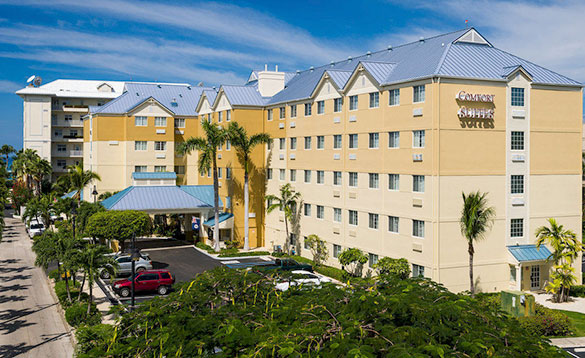 five storey large hotel with cream and yellow painted walls and a car park to the front Comfort Suites/