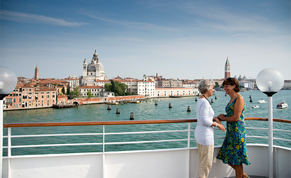Two ladies on the deck of a cruise ship enjoying the view as the ship sails into Venice/