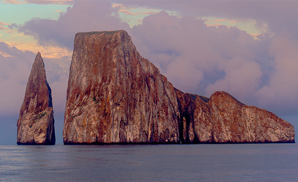large rocky russet coloured island with smaller pointed rocky outcrop at the side/