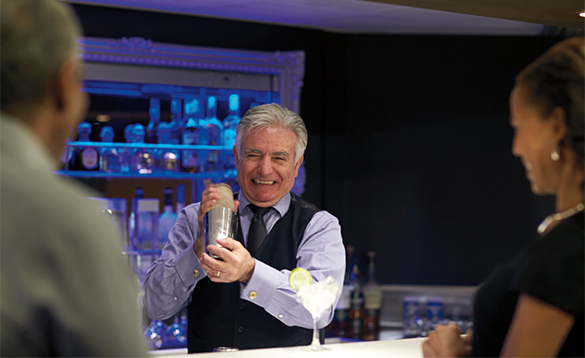 Barman mixing cocktails for a couple in the Gallery Bar on a Holland America cruise ship/
