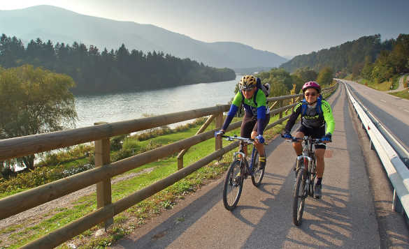 Two cyclists biking beside the River Drava in Slovenia/