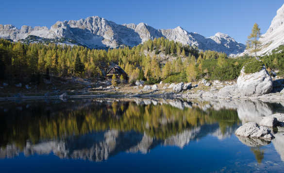 Craggy mountains and fir forests reflected into the clear waters of Double Lake in Slovenia/