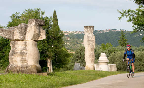 Cyclist biking past stone sculptures in Portoroz, Slovenia/