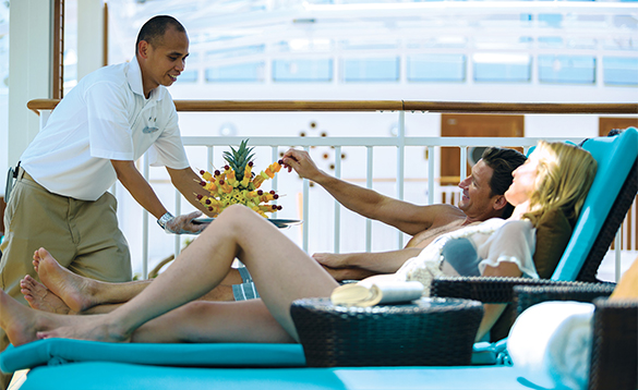 Waiter serving fruit to a couple on sun loungers on board a NCL cruise ship/