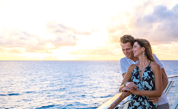 Couple standing at a balcony watching the sunset onboard a NCL cruise ship/