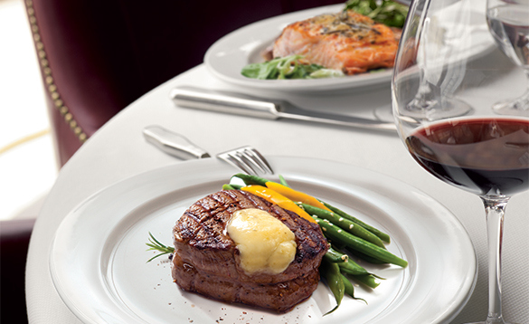 Dinner plate with steak and vegetables next to a glass of wine/