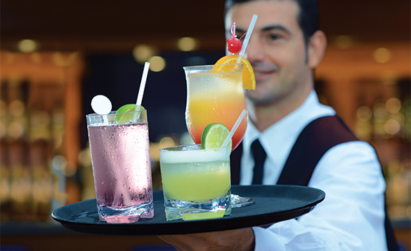 Waiter carrying three cocktails on a tray/