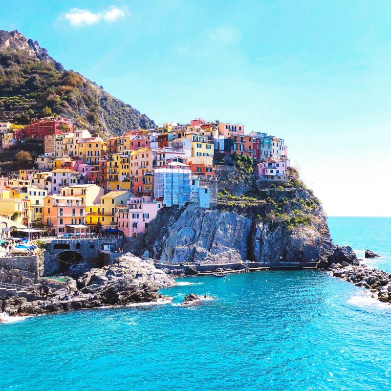 Mediterranean Colourful buildings of a coastal village perched on a rocky cliffside overlooking vibrant blue sea water