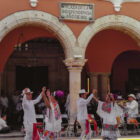 Dancers in traditional white Mexican attire performing beneath the arches of Plaza de la Independencia.