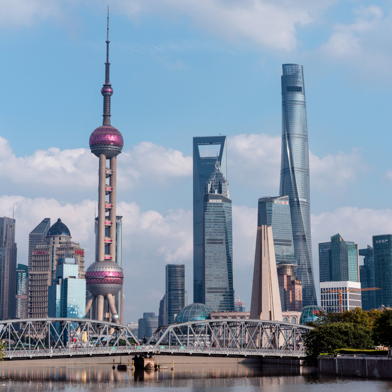 Shanghai The Shanghai skyline featuring the Oriental Pearl Tower and modern skyscrapers rising behind a steel truss bridge.