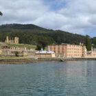 Historic stone convict ruins of Port Arthur situated along the edge of a calm bay.