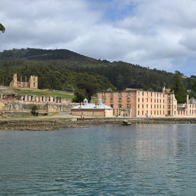 Historic stone convict ruins of Port Arthur situated along the edge of a calm bay.