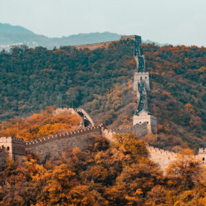 Scenic view of the Great Wall of China winding along a mountain ridge surrounded by vibrant autumn foliage.