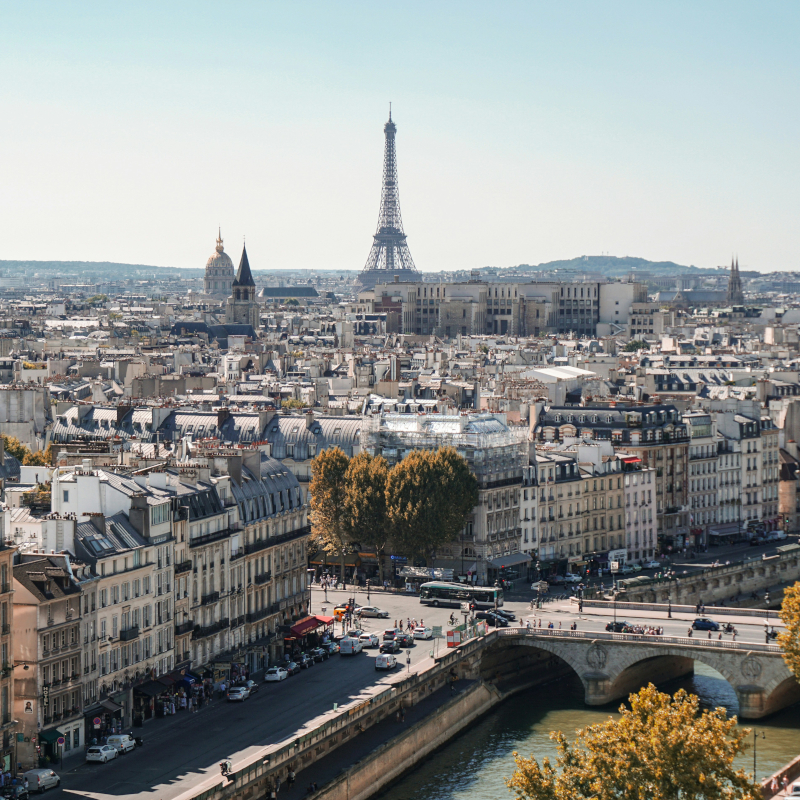 Aerial view of Paris showing city streets, bridges, and the Eiffel Tower in the distance.