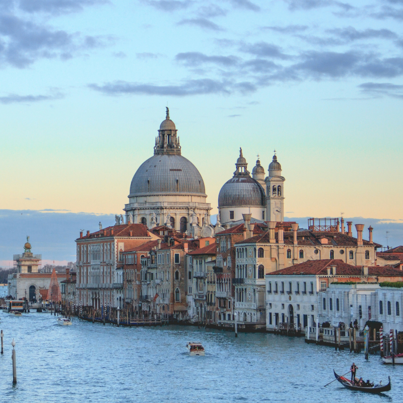 View across a Venice canal toward historic domed churches and waterfront buildings.