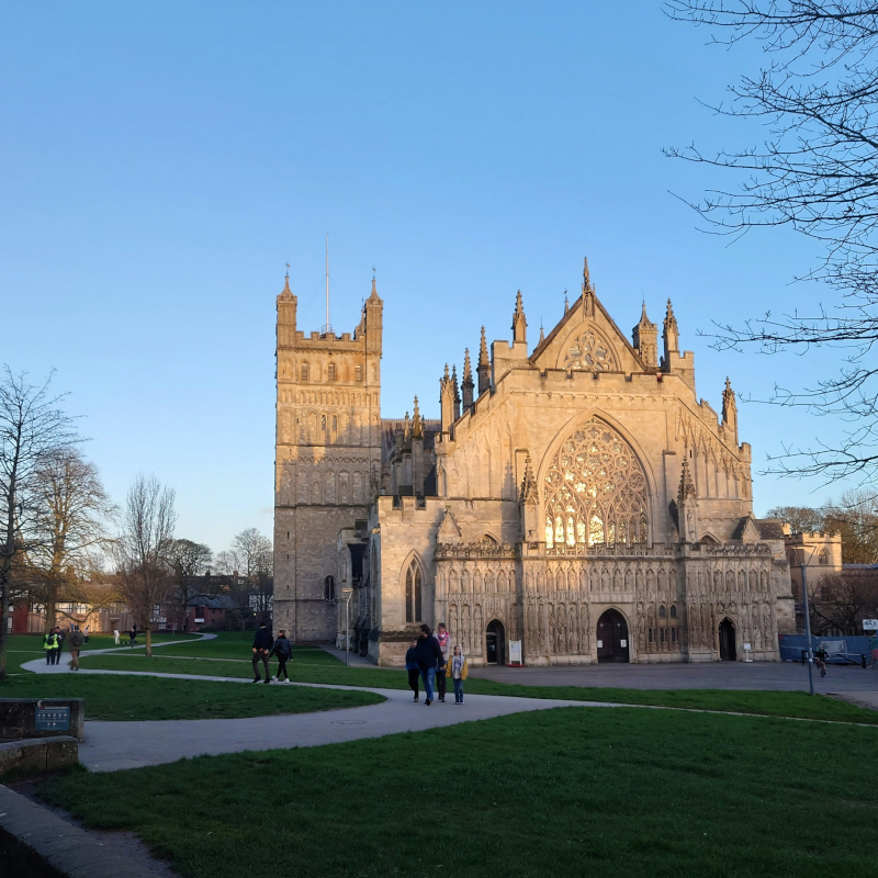 Historic stone cathedral with detailed ornate architecture set alongside a green lawn and footpaths.