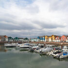 Marina filled with docked boats and yachts against a backdrop of colourful waterfront residential buildings.